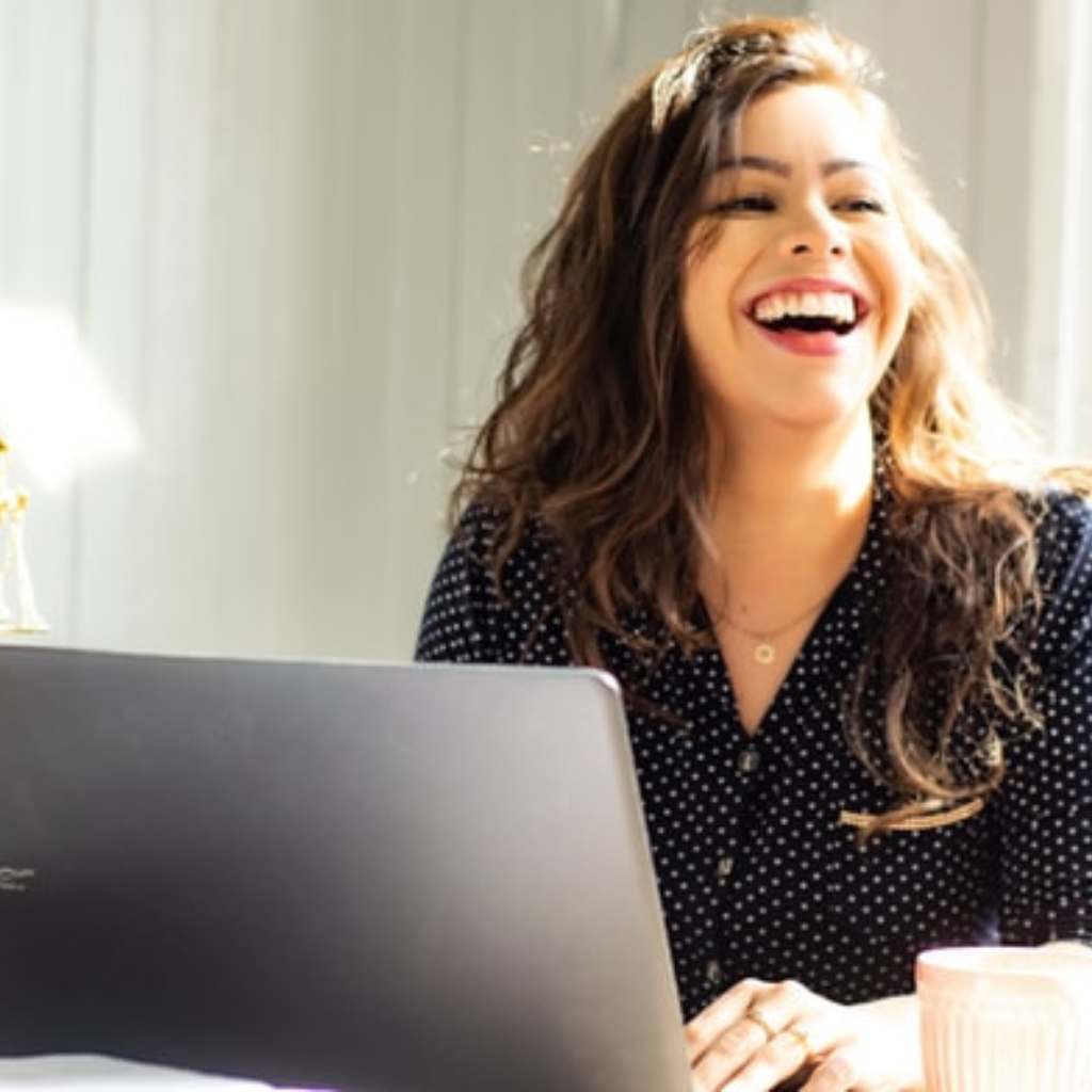 A woman laughing at a computer 